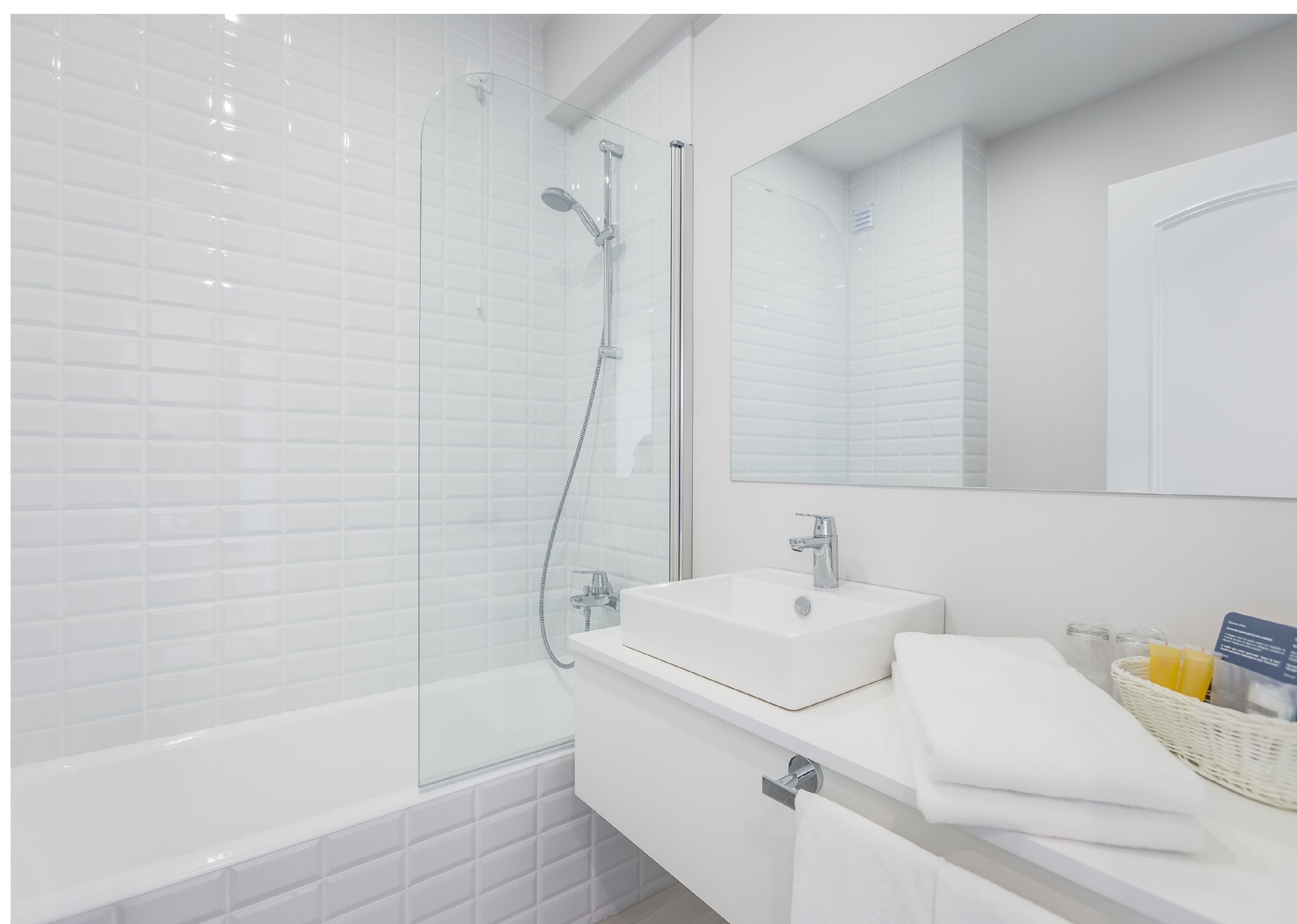 A modern bathroom with a glass-enclosed shower, a white sink, and a mirror above the sink.