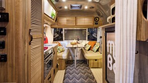 Un intérieur de camping-car compact comprenant un coin cuisine, un espace salon et une petite table avec une lampe.