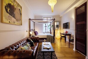 A room with a leather sofa, a bed with a canopy, a desk with a chair, and a television on the wall. - 66 Guldsmeden  (Copenhagen)