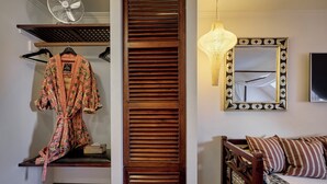 A room with a wooden slat partition, a hanging light fixture, a mirror with a decorative frame, a wooden bed with patterned bedding, and a fan on a shelf. - 66 Guldsmeden  (Copenhagen)