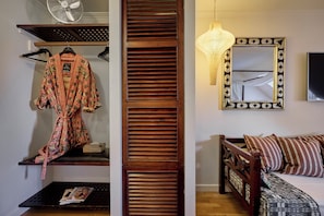 A room with a wooden slat partition, a hanging light fixture, a mirror with a decorative frame, a wooden bed with patterned bedding, and a fan on a shelf. - 66 Guldsmeden  (Copenhagen)