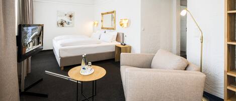 Ein Hotelzimmer mit Bett, Sofa, kleinem Tisch, Fernseher und Lampe.