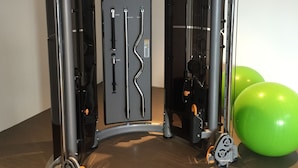 Ein Fitnessraum mit Klimmzugstange, Squat-Rack und zwei grünen Trainingsbällen.