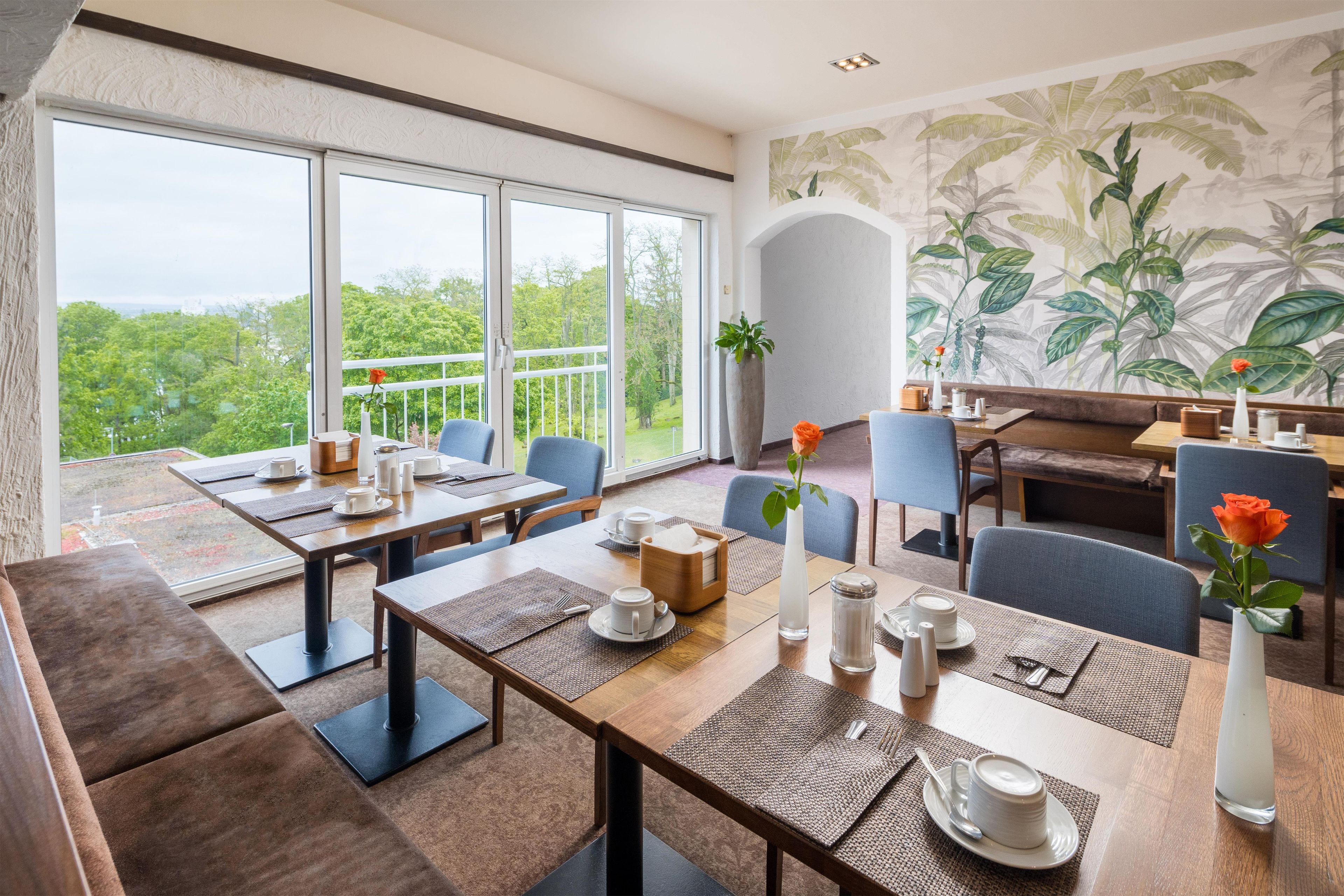 Comedor con mesas, sillas y vistas al exterior con vegetación.