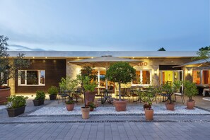 An outdoor seating area with potted plants and umbrellas, a building with a visible 'OO' sign, and a paved walkway. - Best Western Hotel Mainz (Mainz)