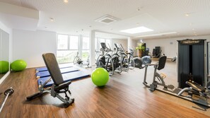 A gym with exercise equipment, a weight bench, and green exercise balls. - Best Western Hotel Mainz (Mainz)