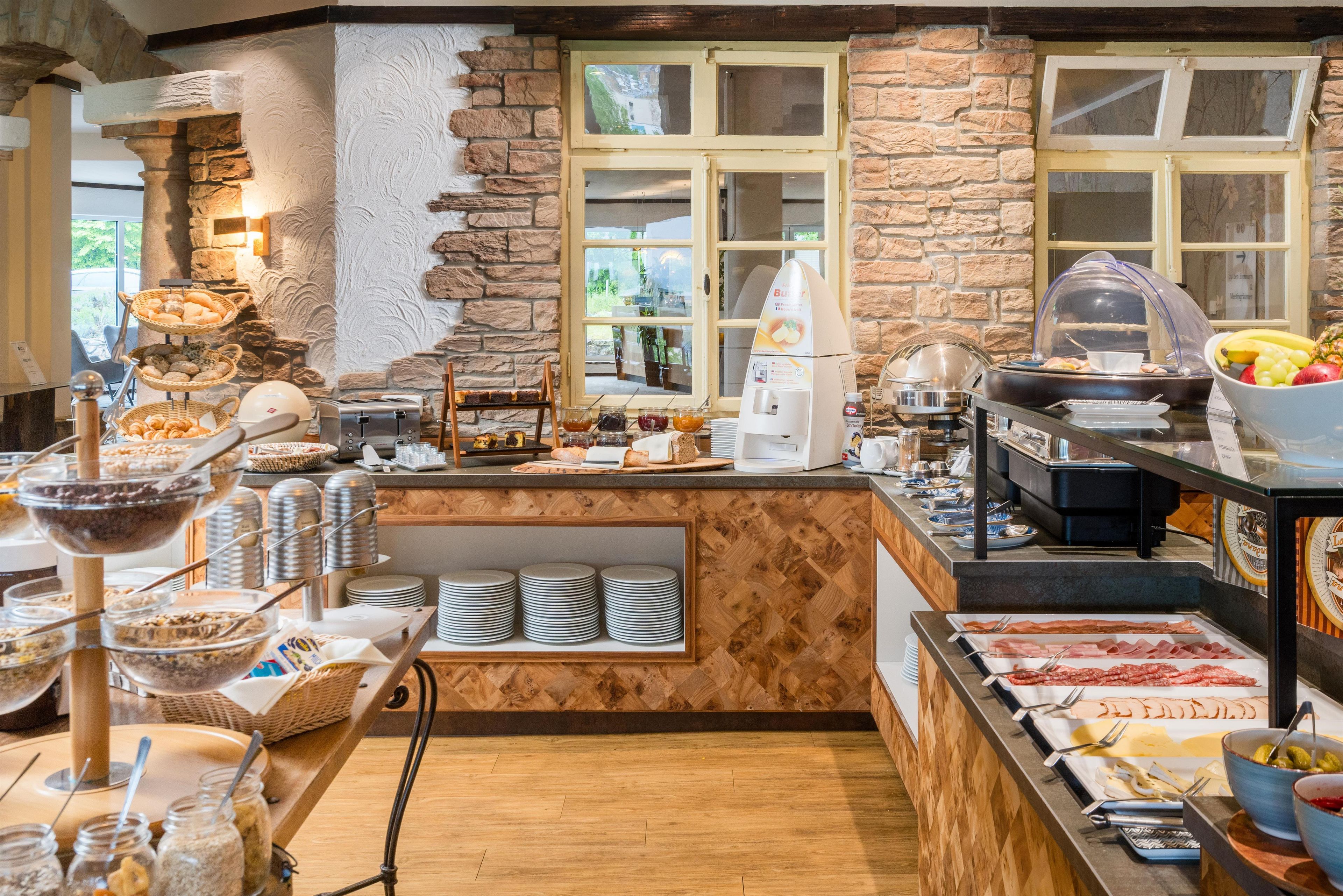 A breakfast buffet with various food items, a coffee machine, and a fruit bowl.