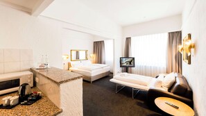 A hotel room with a bed, a sofa, a TV, a small table, a microwave, a coffee maker, and a minibar. - Best Western Hotel Mainz (Mainz)