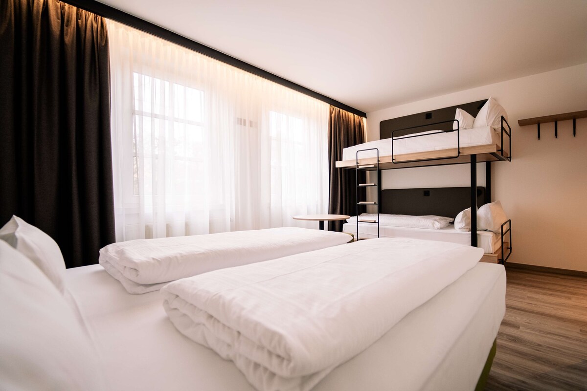 A hotel room with two single beds and a bunk bed.