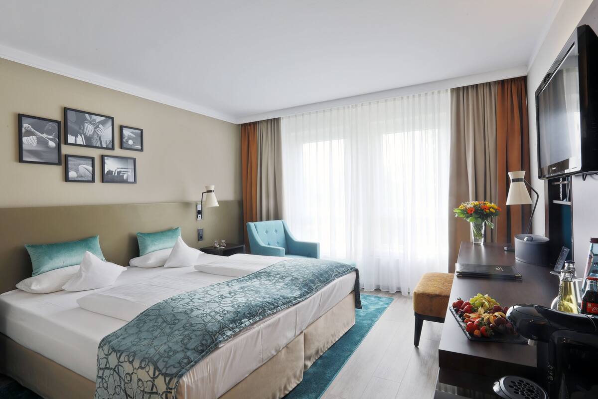A hotel room with a large bed, a desk with a laptop, a chair, a TV, and a coffee maker.