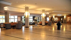 A spacious lobby with high ceilings, large windows, and modern lighting fixtures. - Court Hotel (Halle Westphalia)