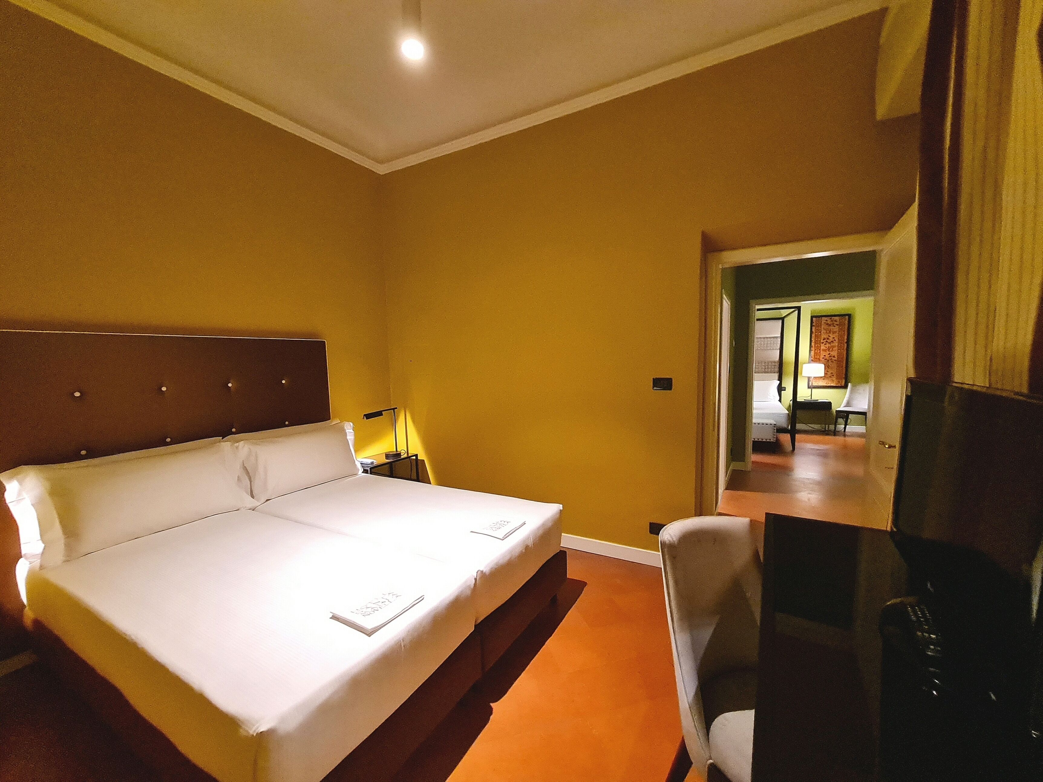 A hotel room with a large bed, a desk, and a chair.