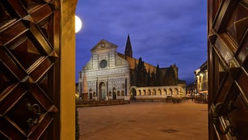 Un edificio storico con una cupola centrale e finestre ad arco, visibile attraverso un'apertura di una porta in legno.