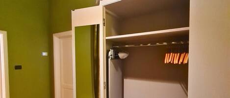 Une pièce avec un mur vert, une porte blanche et un placard contenant des chaussures et une serviette.