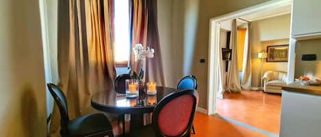 A dining area with a round table, two chairs, and a vase with flowers.