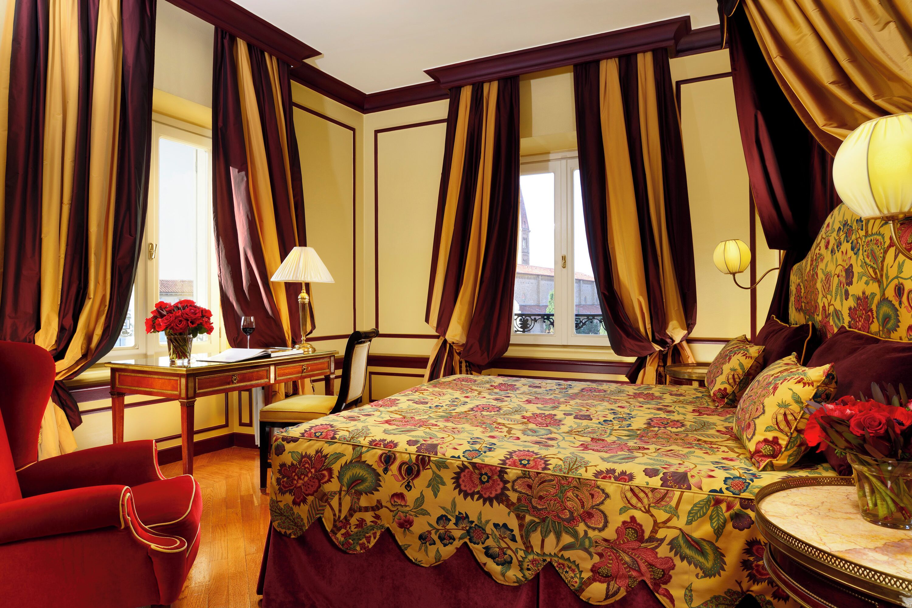 A hotel room with a bed, a desk, a chair, and a window with curtains.