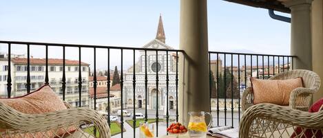 A balcony with wicker furniture, a pitcher of water, and a glass of orange juice.