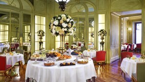 Un comedor formal con varias mesas preparadas para el desayuno, mostrando una variedad de pasteles y frutas.