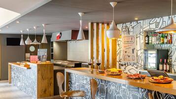 A modern bar area with a central island, bar stools, hanging pendant lights, and a wall with a food and drink illustration.