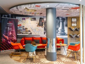 A modern lounge area with a map wall, a large cylindrical column, and colorful seating. - ibis Bilbao Barakaldo (Barakaldo)