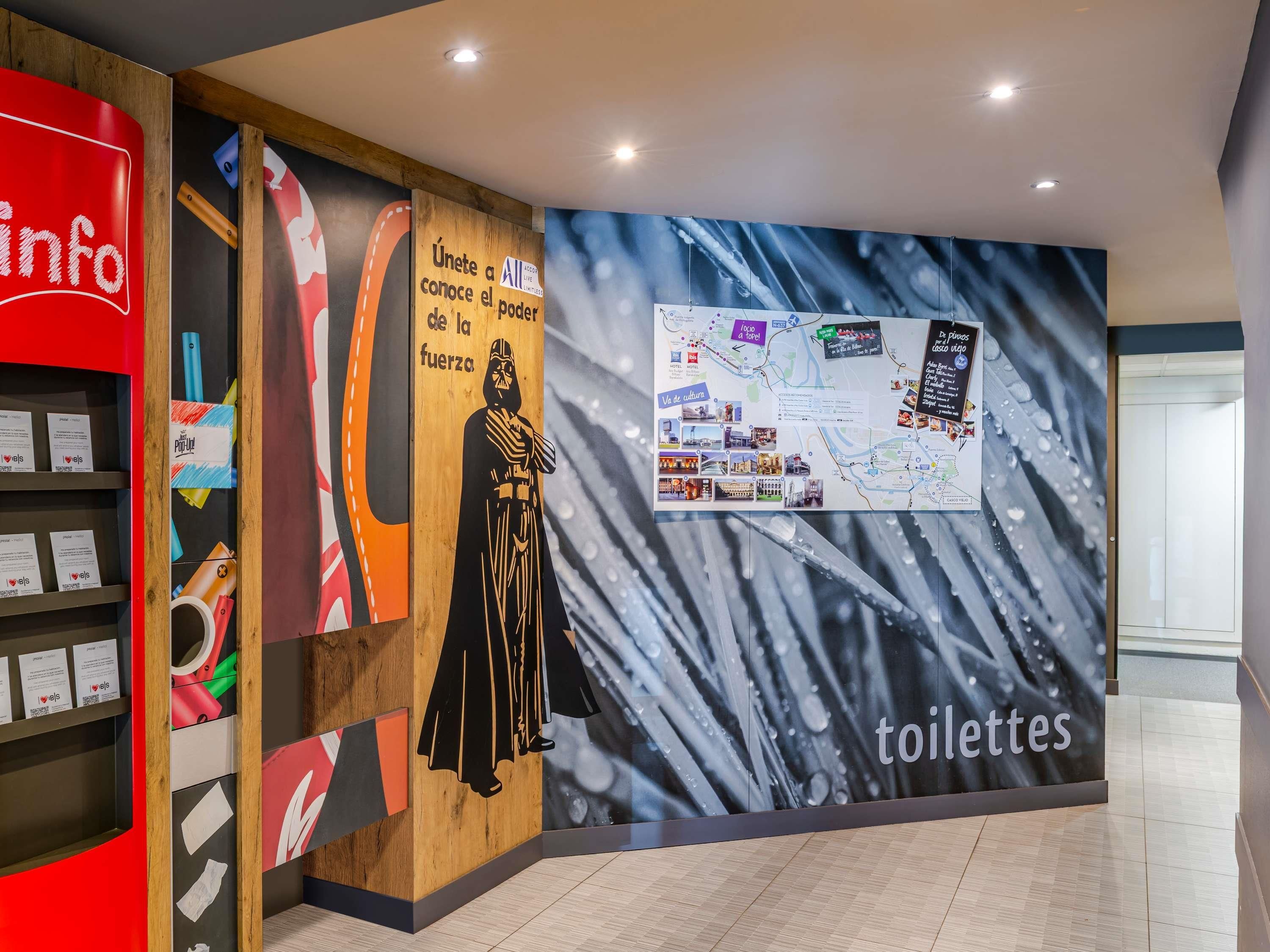 Un baño con un mapa, una figura de Darth Vader y un letrero que dice 'toilettes'.