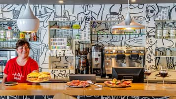 A bar area with a coffee machine, a sign that reads 'WELCOME TO YOUR COMFORT ZONE,' and a person serving food.