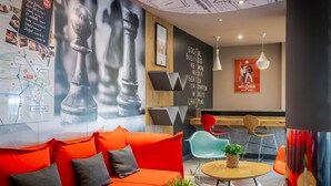 A modern interior with a red sofa, a map on the wall, and a 'Social Business' sign. - ibis Bilbao Barakaldo (Barakaldo)