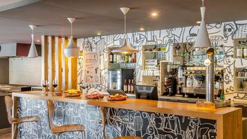 Una zona de bar con mostrador, taburetes y un mural al estilo grafitis en la pared.