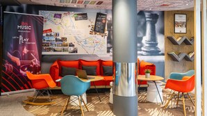 A modern lounge area with a map wall, a large cylindrical column, and colorful seating. - ibis Bilbao Barakaldo (Barakaldo)