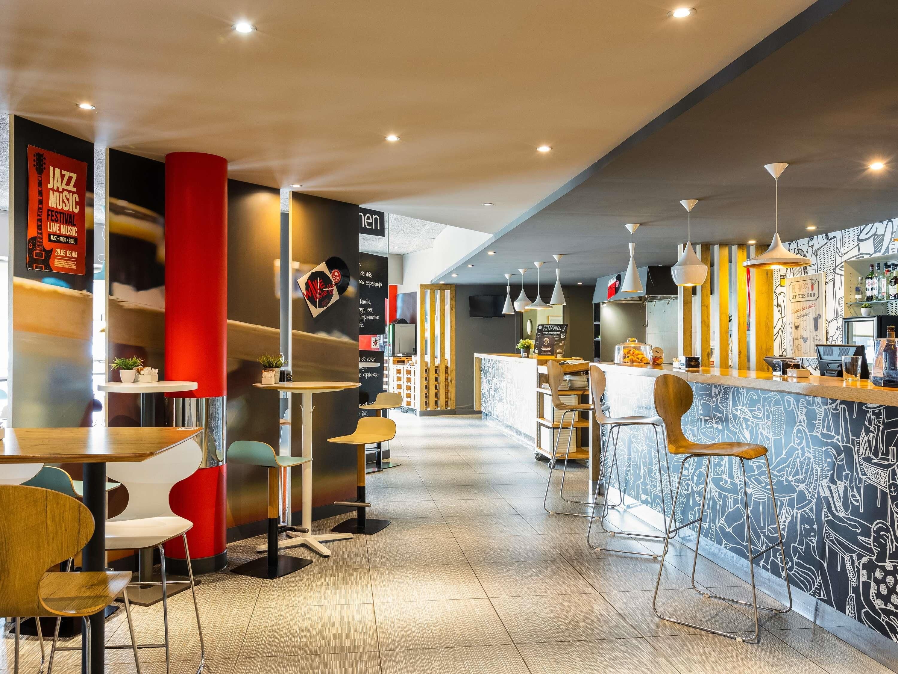 Un área de bar moderna con mostrador, asientos y un mural.