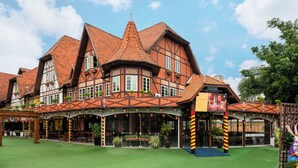 A traditional building with multiple windows, a green lawn, and a covered outdoor seating area. - ibis Blumenau (Blumenau)