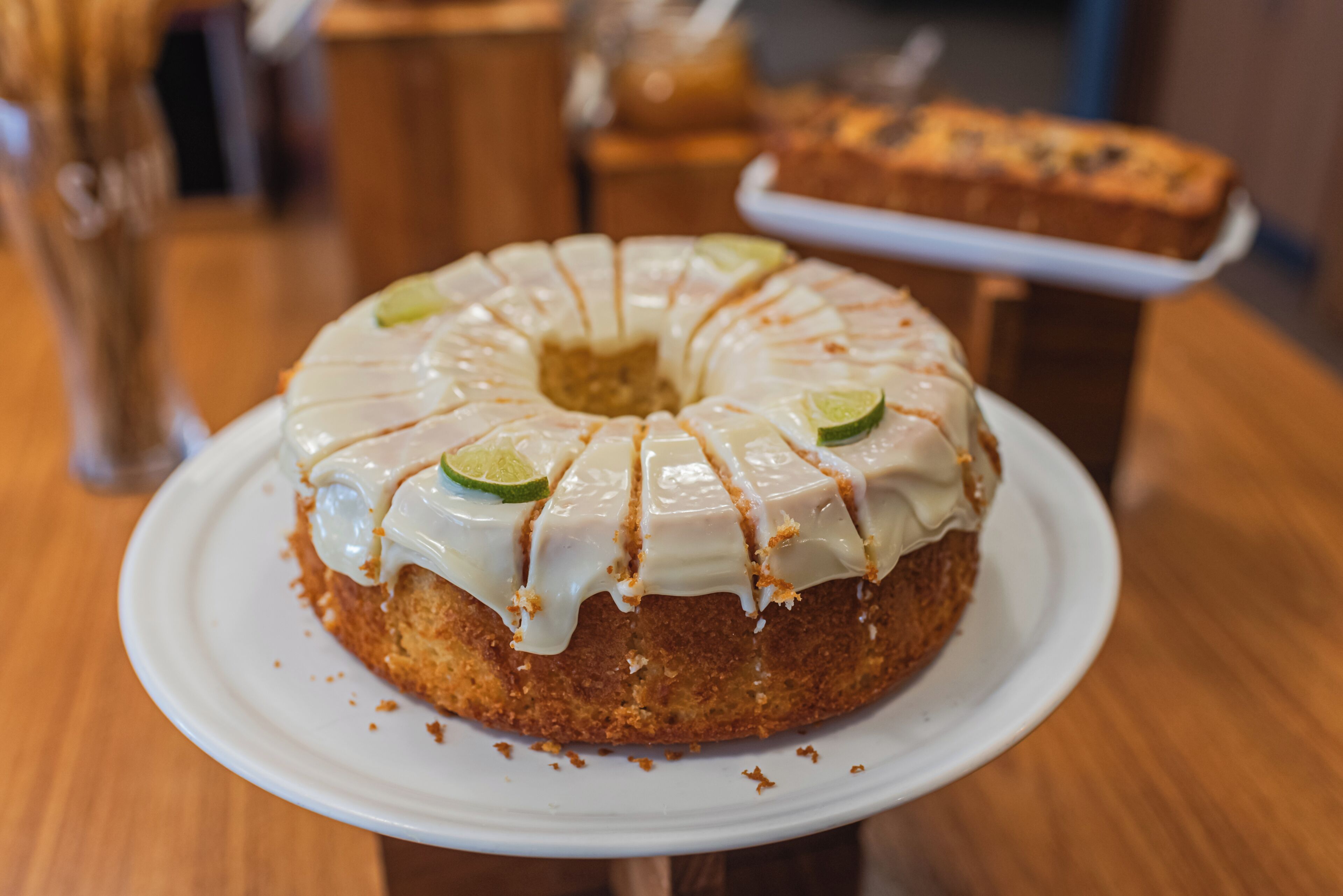 A cake with white icing and lime slices on a white plate.