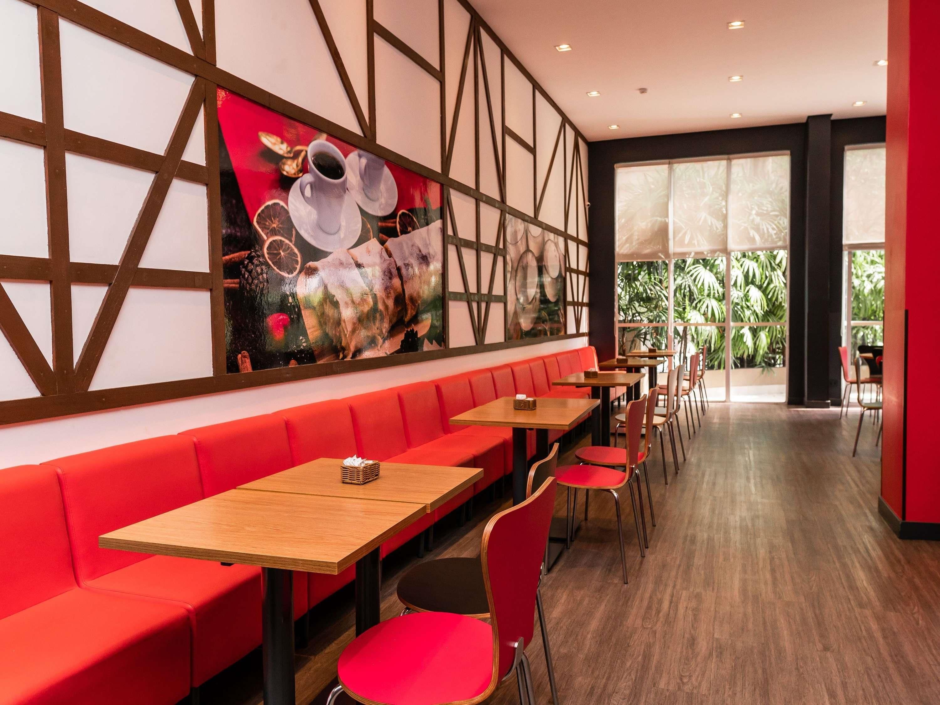 A restaurant interior with red seating, wooden tables, and a large wall mural.