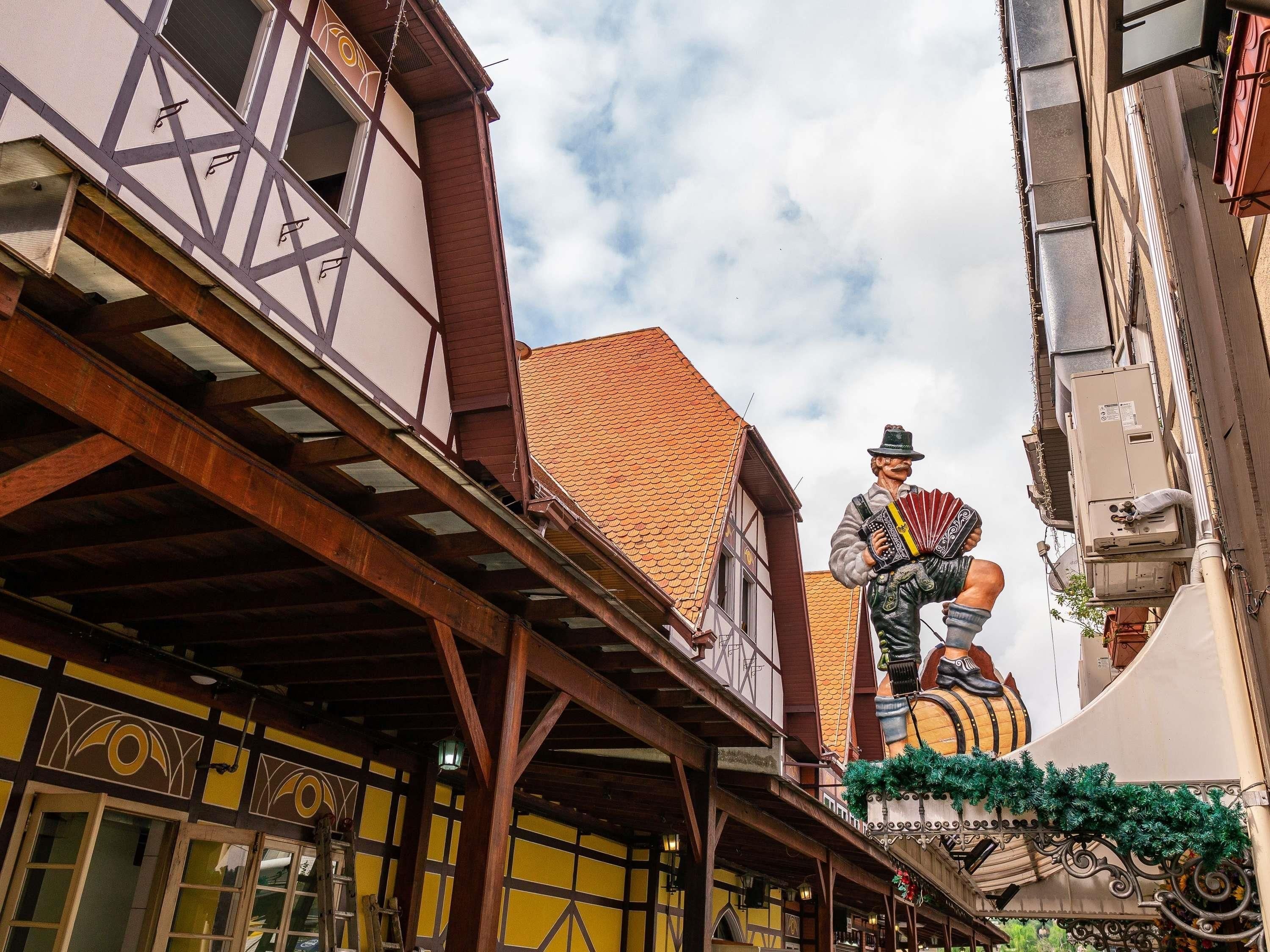 A traditional half-timbered building with a balcony and a statue of a man playing a bagpipe.