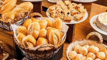 Un buffet proposant une variété de pains, de viennoiseries et de gâteaux.