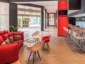 A modern interior with a red sofa, a small table, and a bar area with chairs.