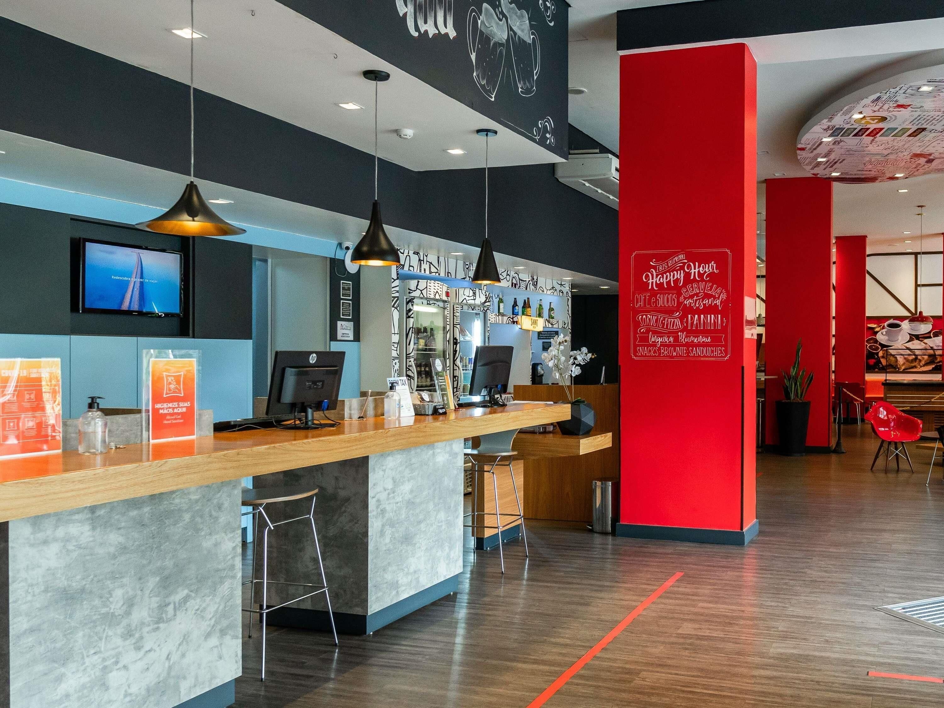 A modern reception area with a counter, seating, and a red accent wall.