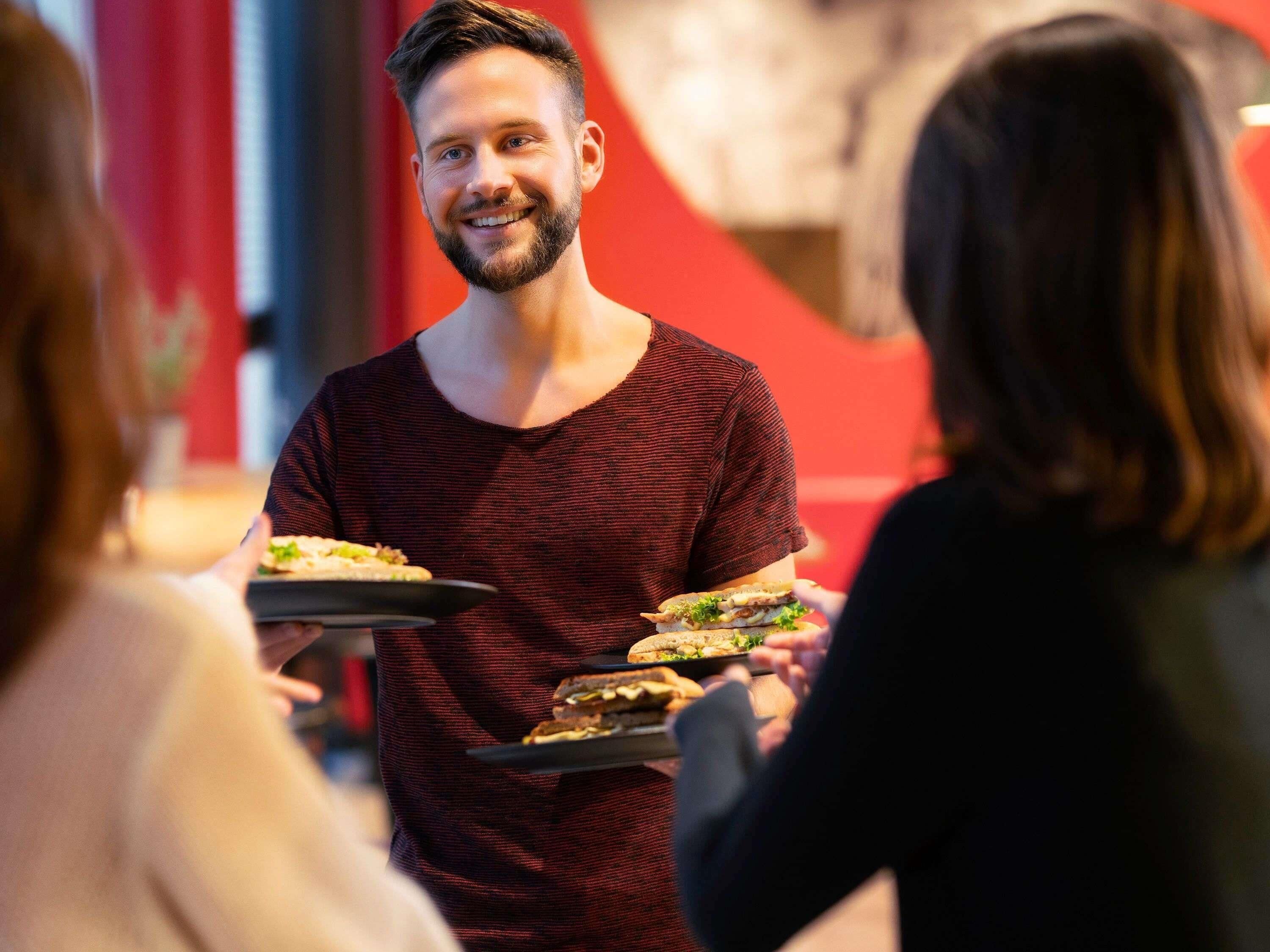 Una persona sirviendo comida a los clientes en un restaurante.