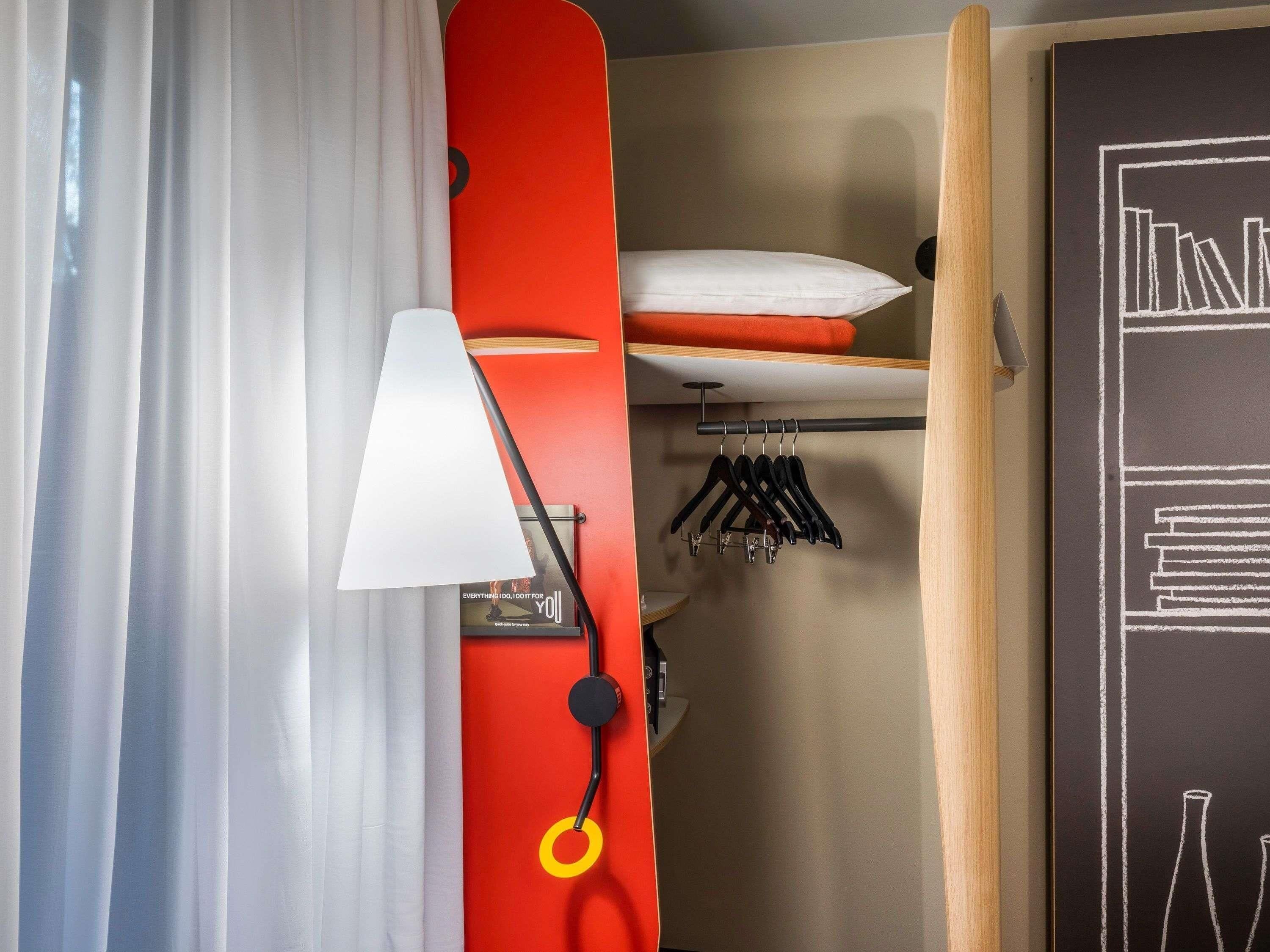 A room with a bed, a hanging light, a closet with clothes, and a chalkboard with text.
