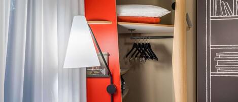 A room with a bed, a hanging light, a closet with clothes, and a chalkboard with text.