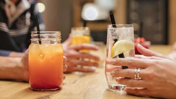 Une table en bois sur laquelle sont posées trois boissons : une dans un bocal et deux dans des verres, avec des pailles et des rondelles de citron.