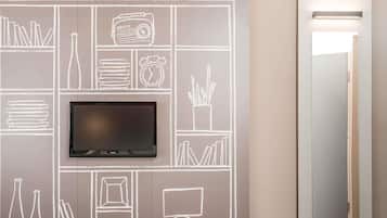 A wall with a flat-screen TV mounted above a chalkboard-style wall art depicting various objects like books, a radio, and a clock.