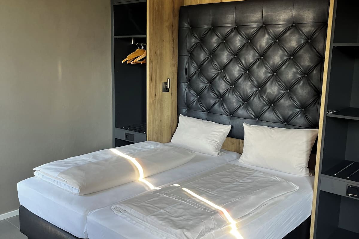 A modern bedroom with a large bed, wooden headboard, and built-in shelving.