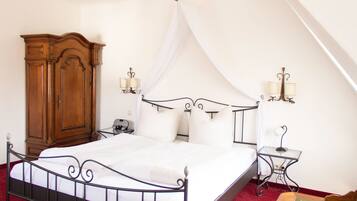 Un dormitorio con una cama con dosel, un armario de madera, dos mesitas de noche con lámparas y una alfombra roja.