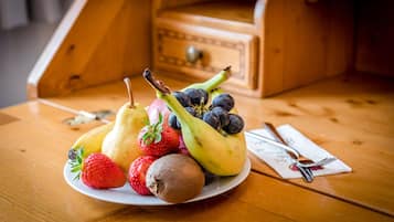 Una mesa de madera con un plato de fruta y una servilleta con cubiertos.