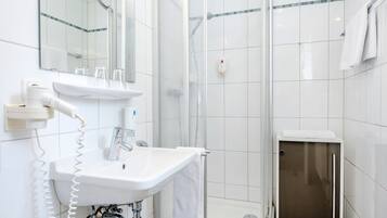 Un baño moderno con ducha de vidrio, un lavabo blanco con espejo y un inodoro.