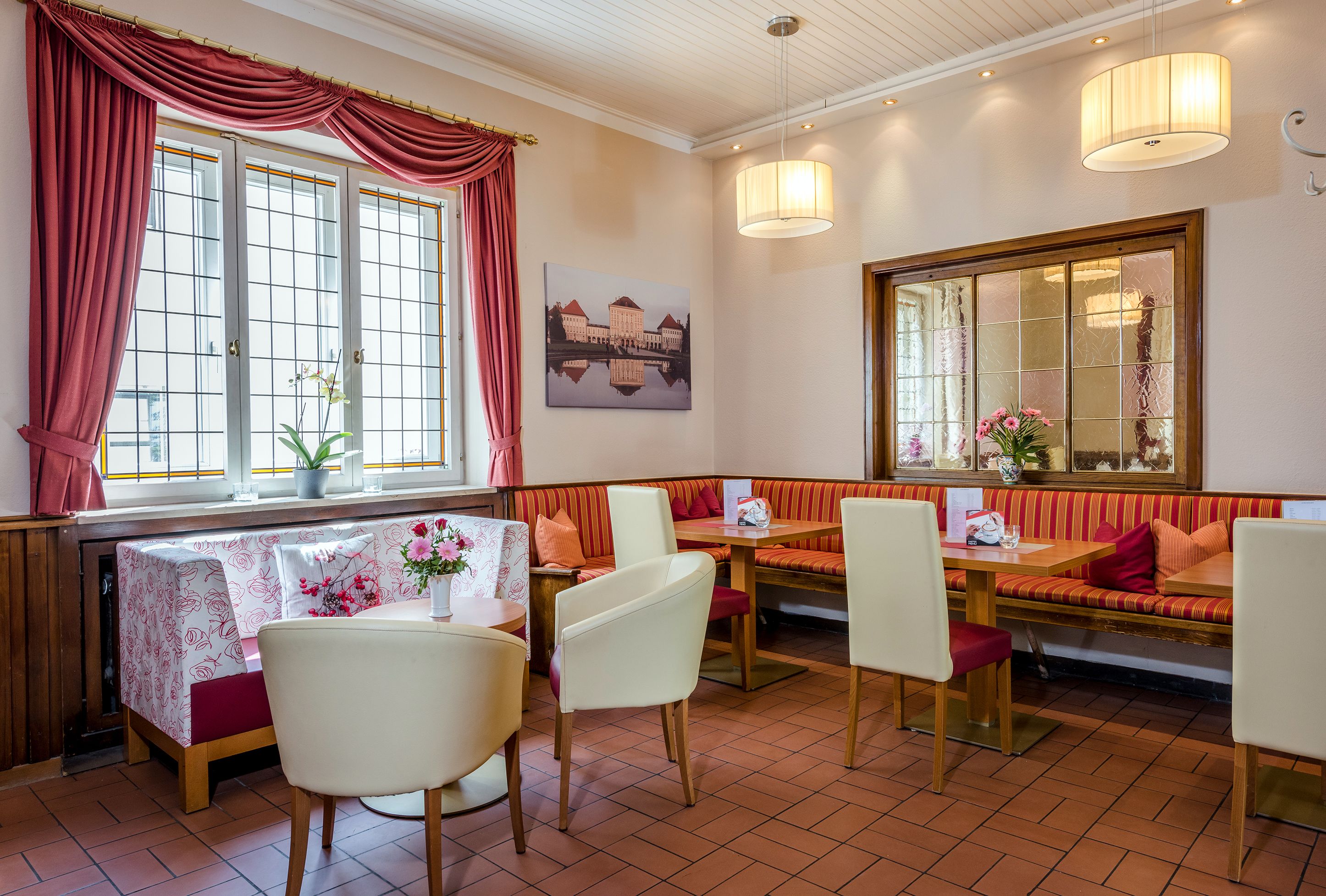 Ein Restaurant mit rotem und weißem Dekor, ausgestattet mit einem großen Fenster, einer Bank und einem Tisch mit Stühlen.