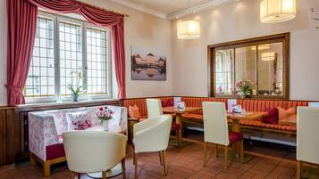 Ein Restaurant mit rotem und weißem Dekor, ausgestattet mit einem großen Fenster, einer Bank und einem Tisch mit Stühlen.