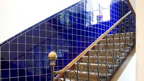 A staircase with blue-tiled walls, wooden steps, and black iron railings. - Hotel Laimer Hof Nymphenburg Palace Munich (Munich)