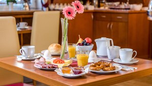 A breakfast table with various food items, a vase with flowers, and a coffee station. - Hotel Laimer Hof Nymphenburg Palace Munich (Munich)